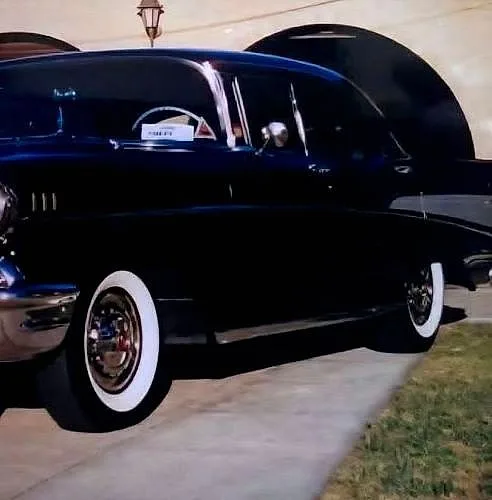 A black 1957 Chevrolet Bel Air with chrome trim and whitewall tyres